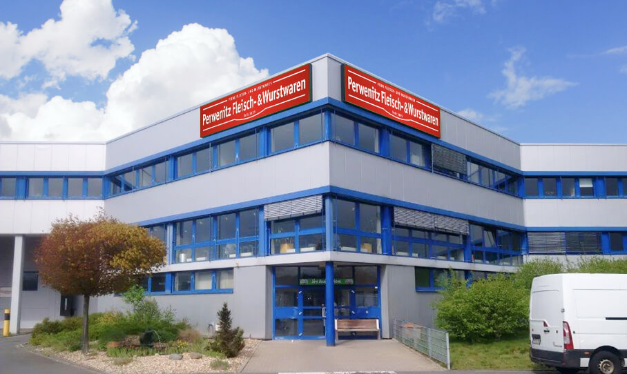 Bürogebäude mit blauer Fassade und dem Firmenlogo von Perwenitz Fleisch- & Wurstwaren an der Ecke des Gebäudes