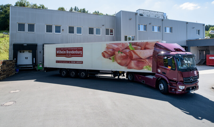 Wilhelm Brandenburg LKW mit Fleischmotiv vor einem grauen Industriegebäude