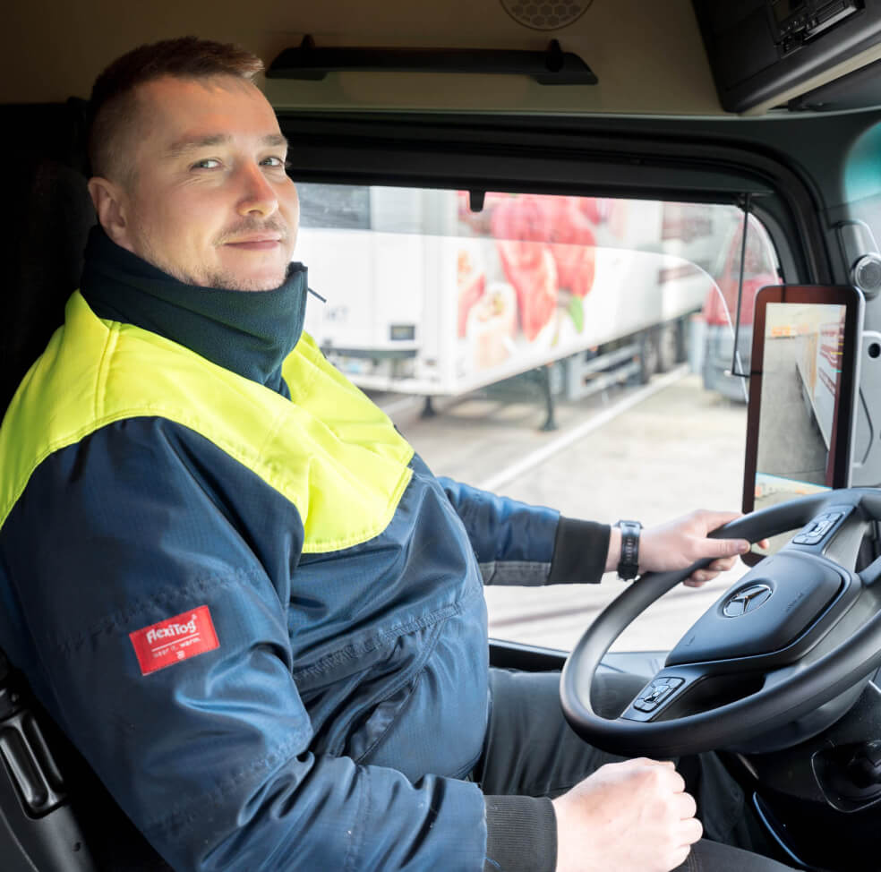 LKW-Fahrer von Wilhelm Brandenburg im Fahrerhaus, trägt blaue Jacke mit gelbem Schutzkragen