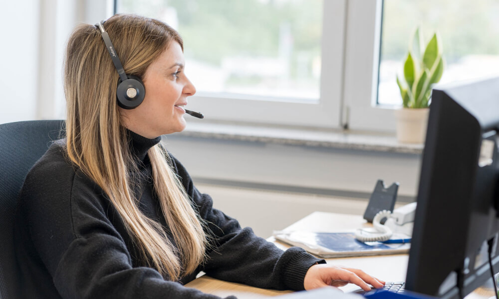 Mitarbeiterin mit Headset am Arbeitsplatz bei Wilhelm Brandenburg