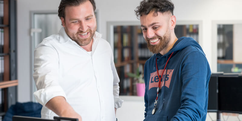 Zwei Kollegen bei Wilhelm Brandenburg arbeiten zusammen am Computer im Büro