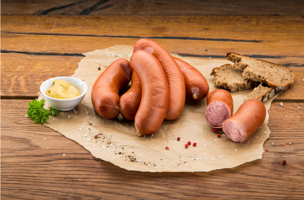 Geräucherte Würstchen, angerichtet mit Senf und Brot auf Papier auf einem Holztisch