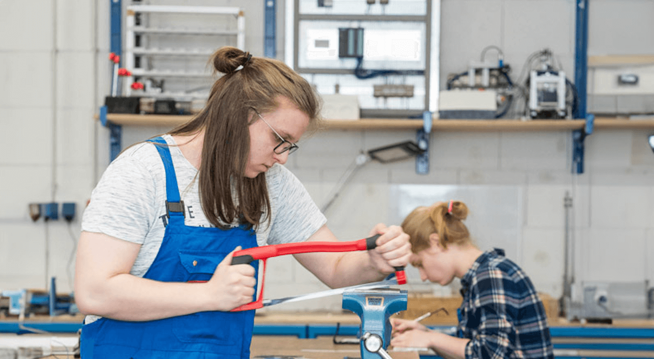 Junger Mensch in der Ausbildung bei Wilhelm Brandenburg arbeitet mit einer Metallsäge in der Werkstatt