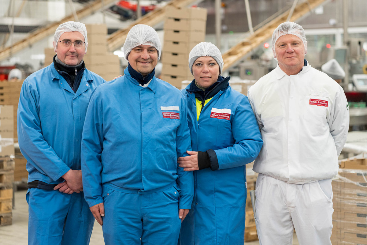 Vier Mitarbeiter von Wilhelm Brandenburg in Schutzkleidung in einer Produktionsumgebung