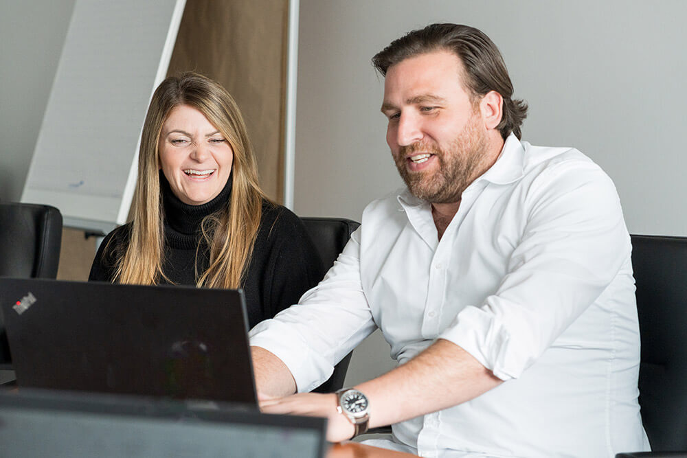 Teammitglieder arbeiten zusammen am Laptop bei Wilhelm Brandenburg