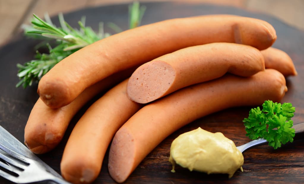 Angerichtete Frankfurter Würstchen mit Senf und Petersilie auf einem dunklen Teller