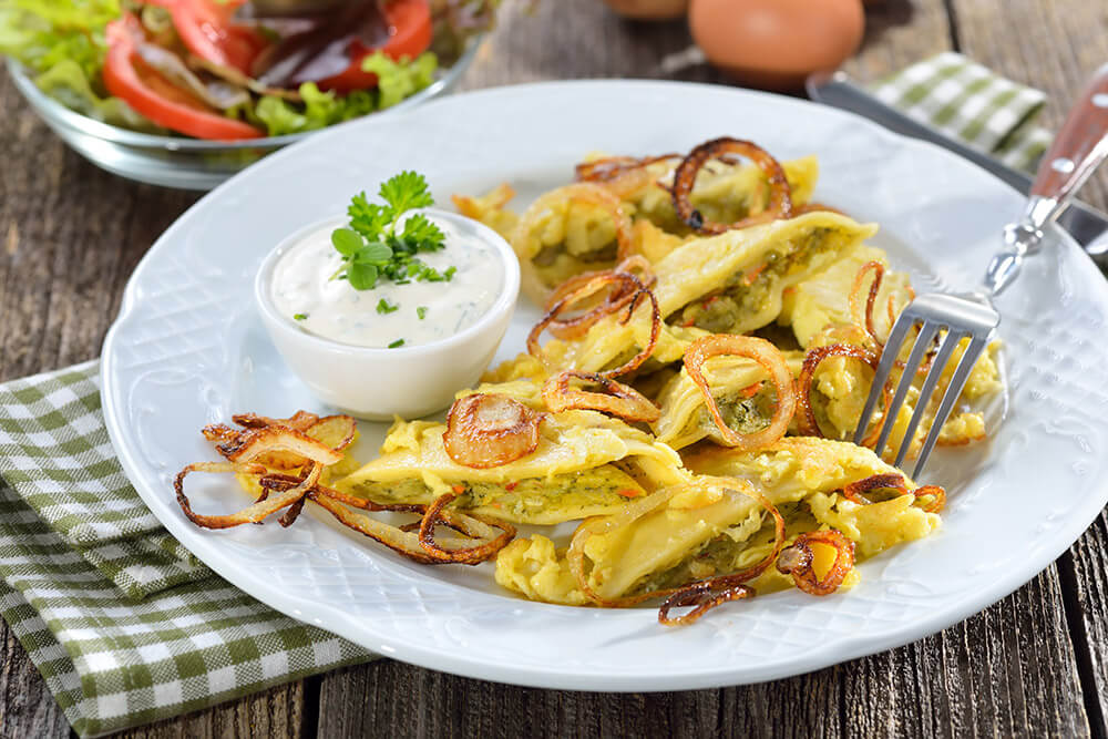 Gebratene Maultaschen mit knusprigen Zwiebeln und Kräuterdip auf rustikalem Teller